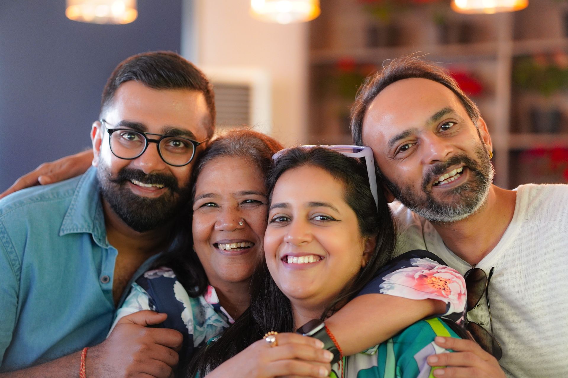 Parents laughing with their grown son and daughter, arms around each other.