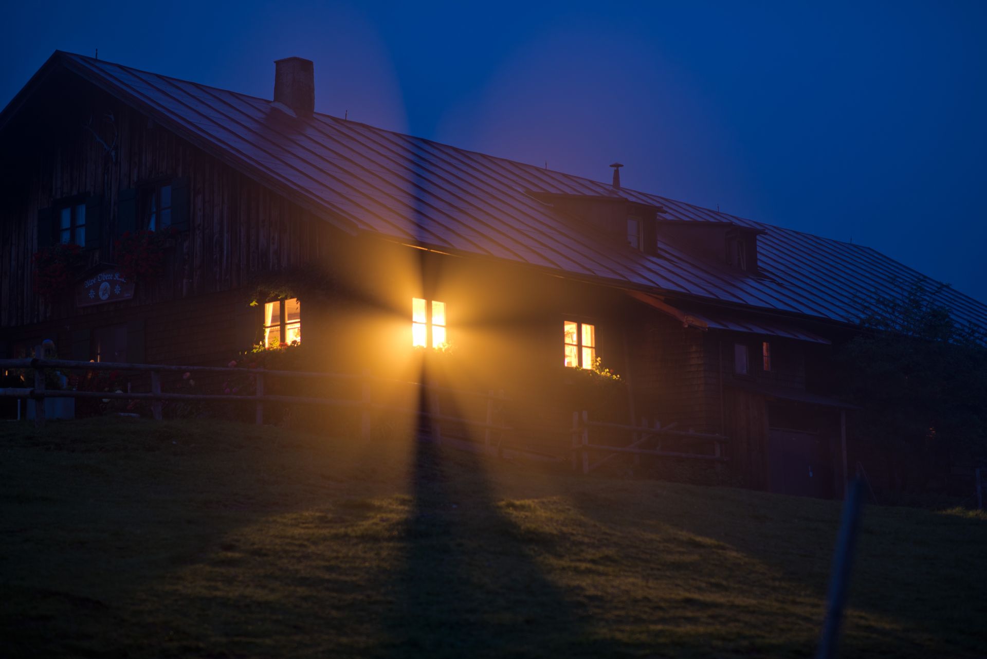A house glowing with warm light in the blue hour of night