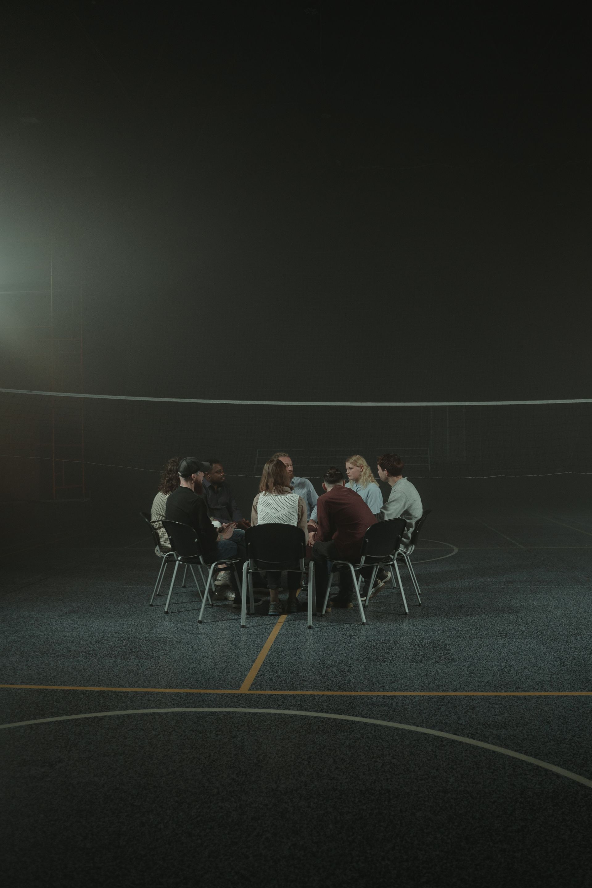 A small support group sits together in a dimly lit circle of chairs.
