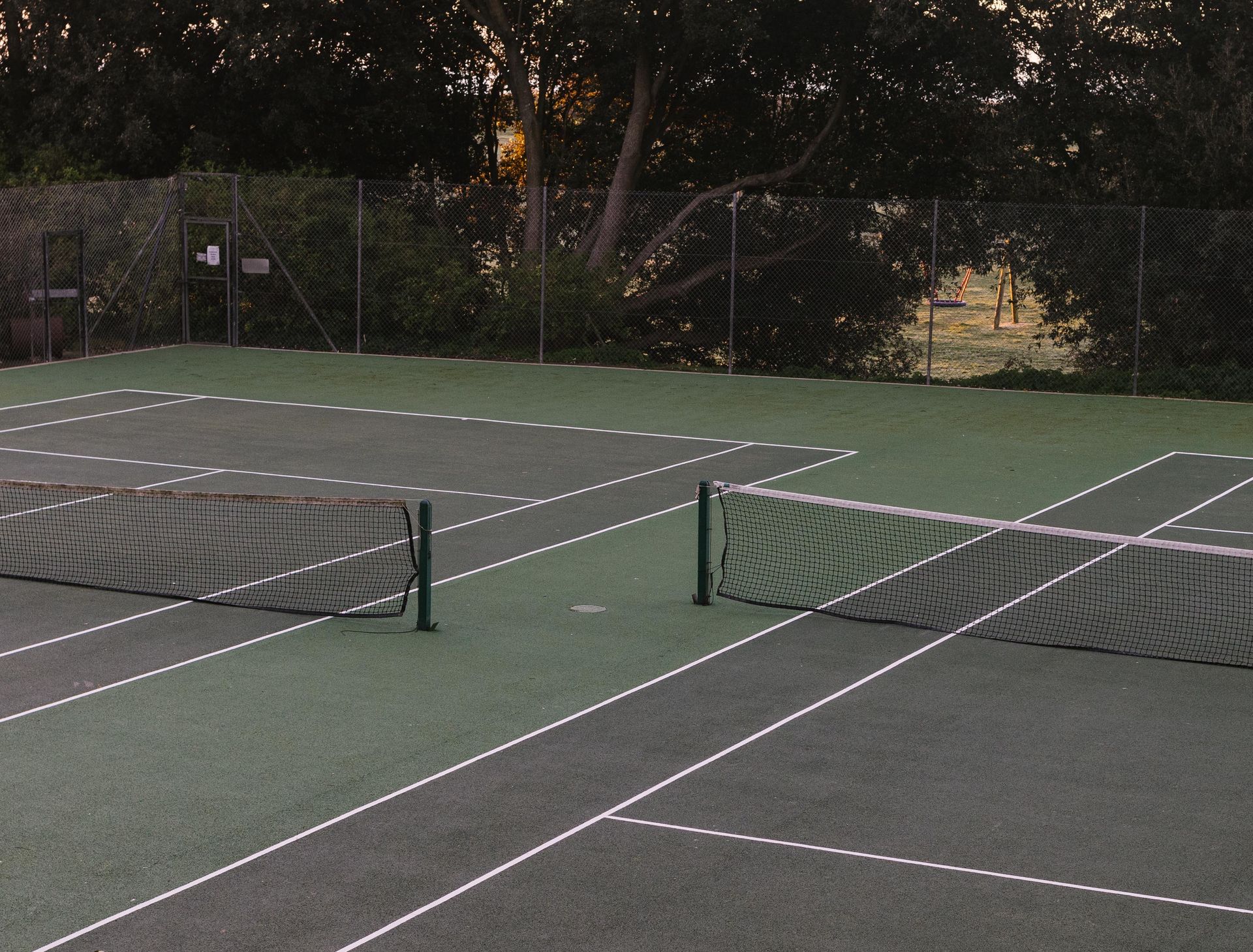 An empty tennis court at dusk, where Michael's story as a nationally ranked junior player began